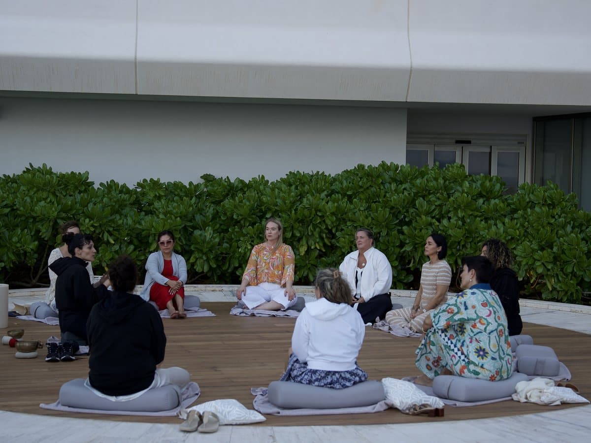Guests seated on cushions in a circle on an open-air terrace